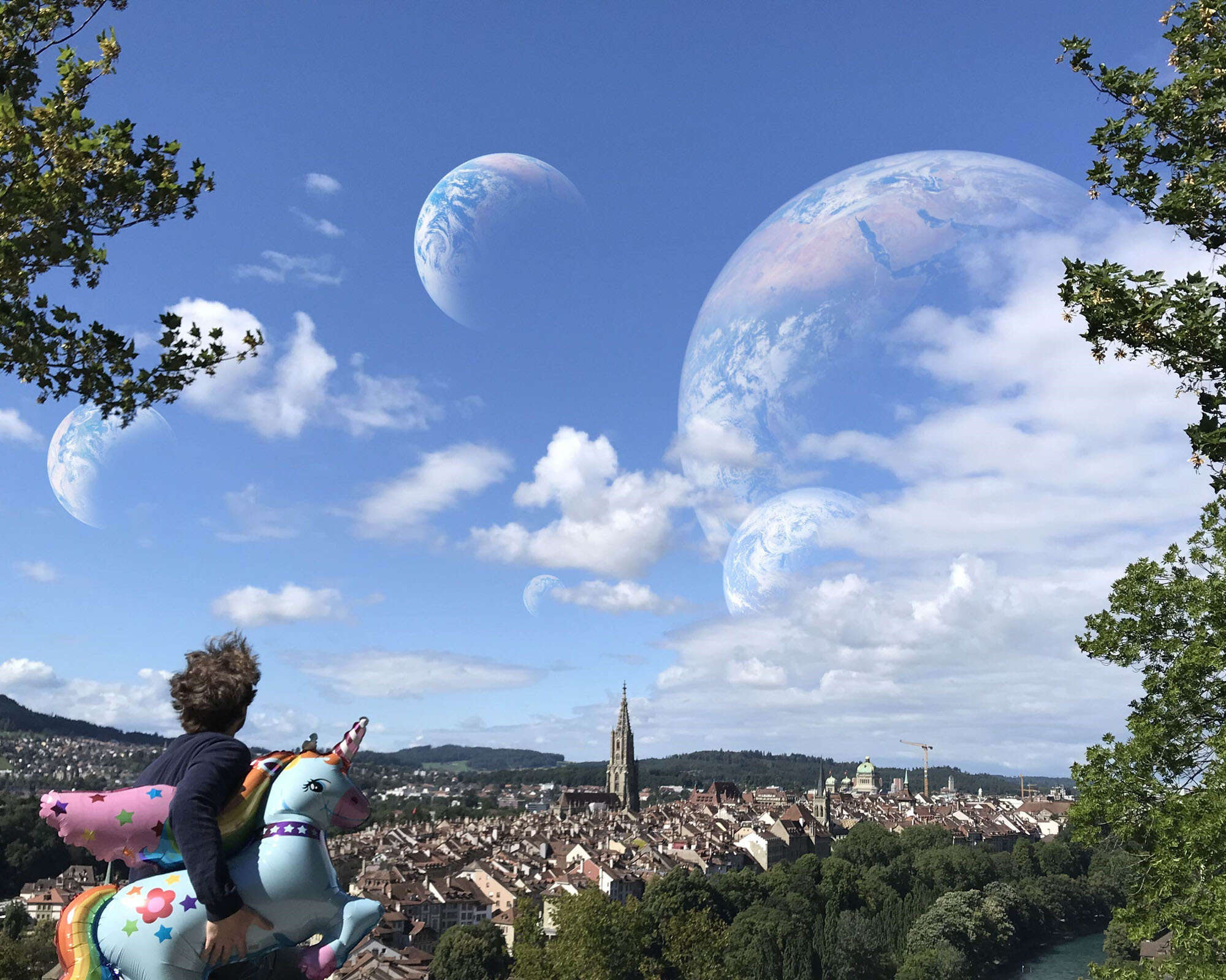 Am Berg steht eine Person mit Einhorn-Luftballon und schaut hoch. Im Himmel schweben vier Erdkugeln..