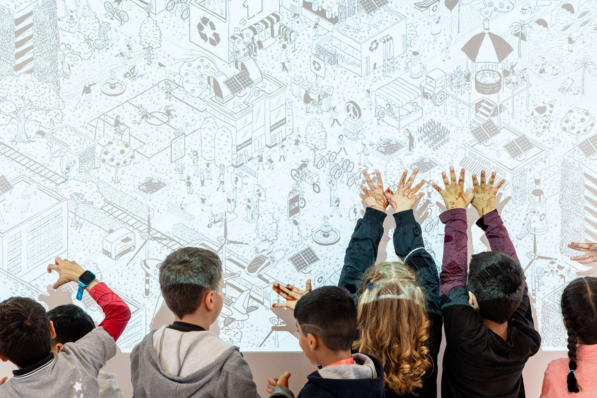 Kinder die an einer Projektion die Hände hochhalten