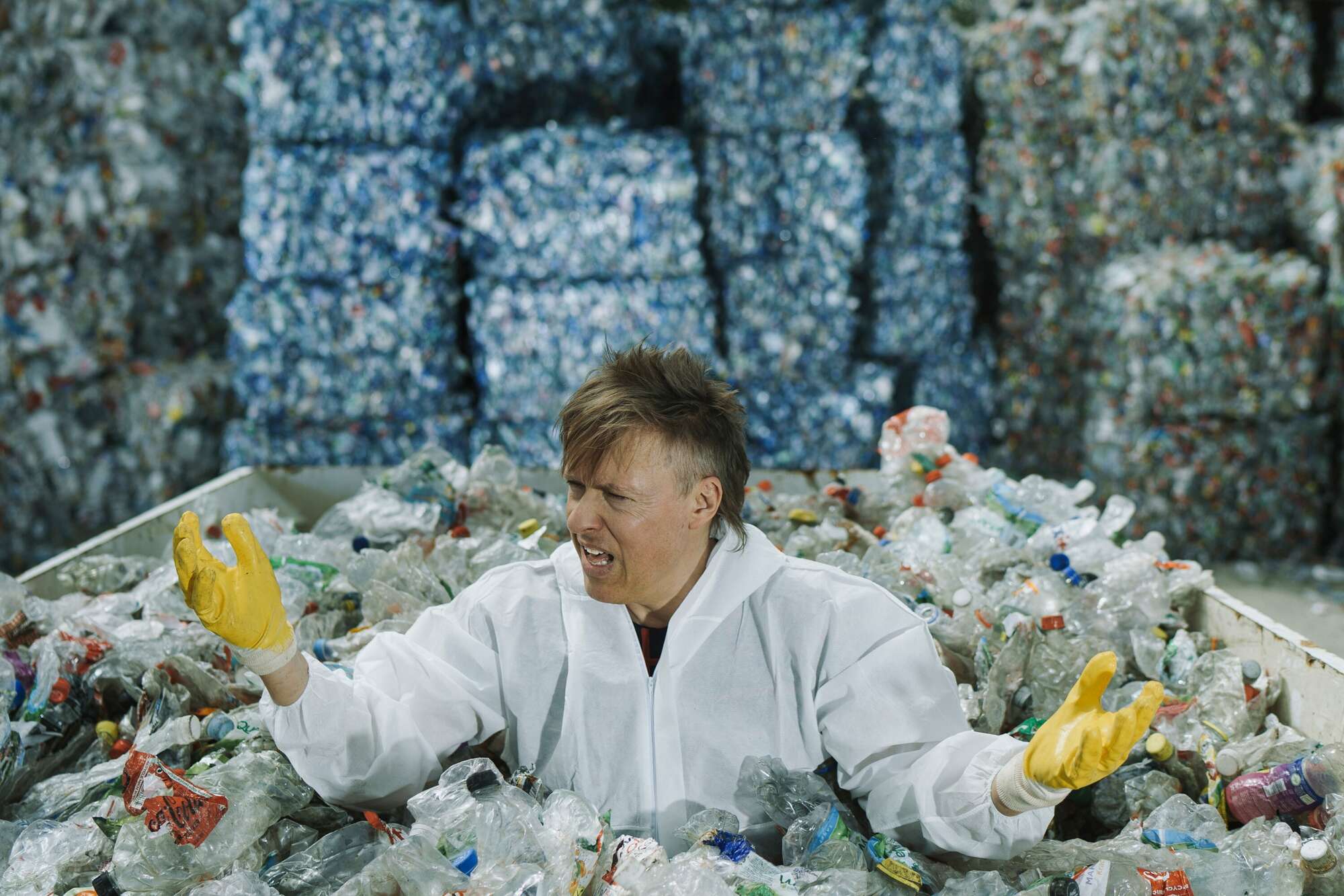 Person sitzt in Menge Plastik, schaut empört